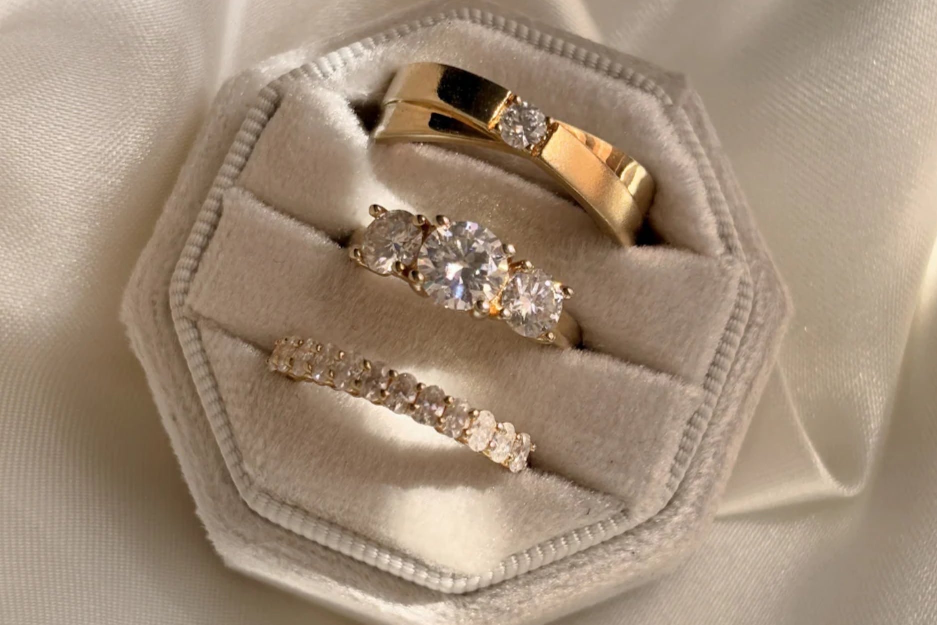 Three diamond rings displayed in a velvet ring box.