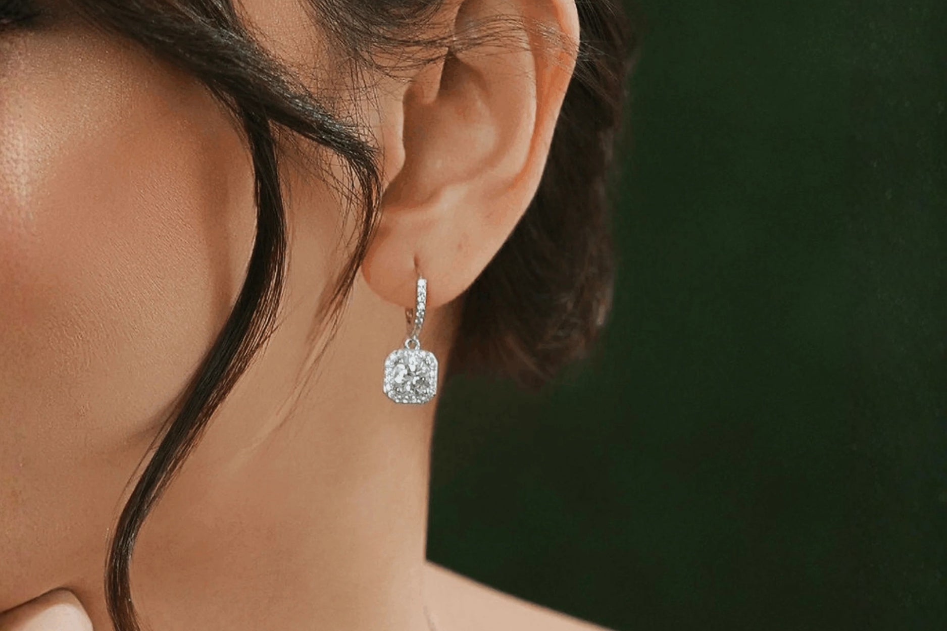 Close-up of a diamond dangling earring with a lab-grown stone, worn on a model's ear