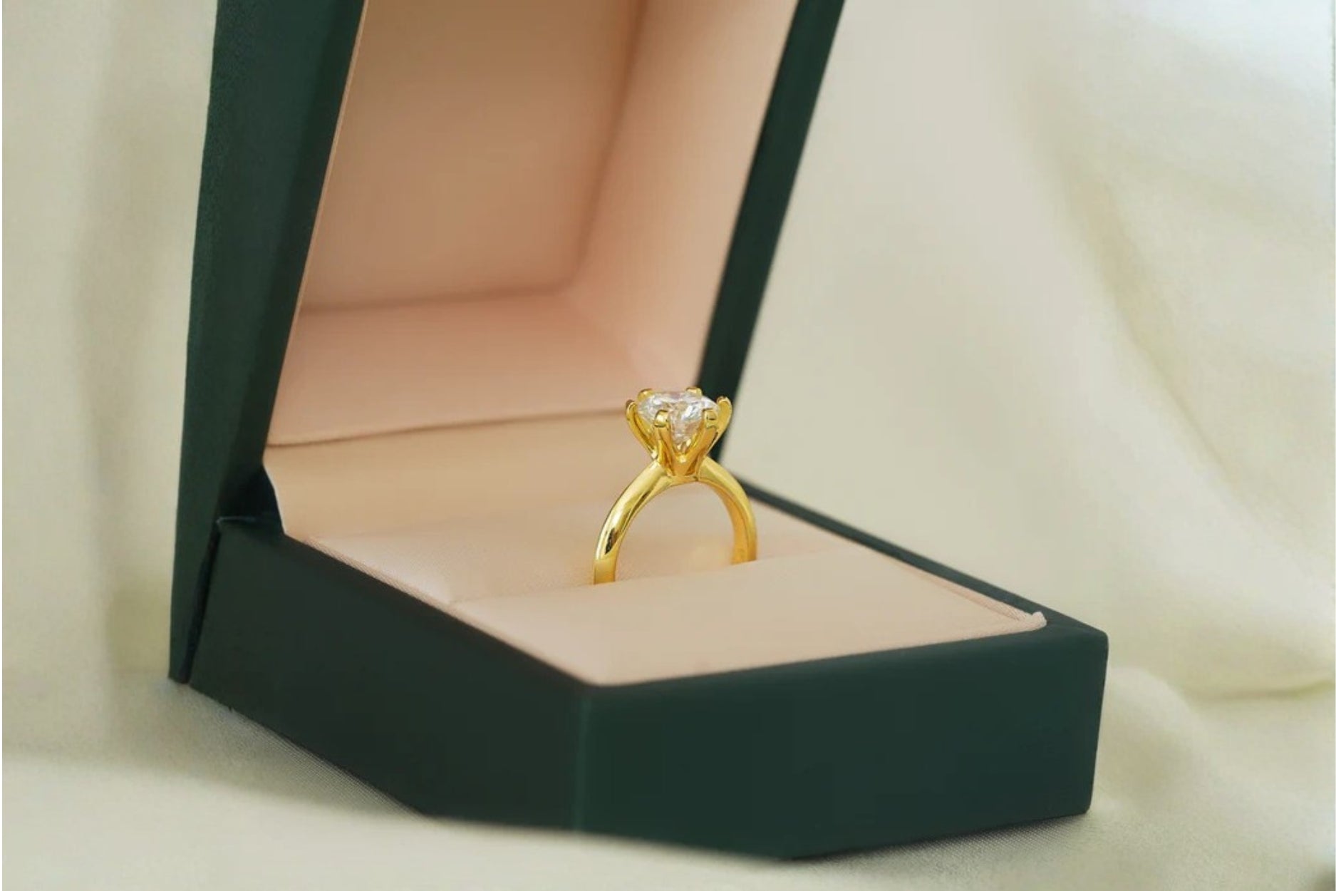 Gold solitaire diamond ring in an open jewelry box.