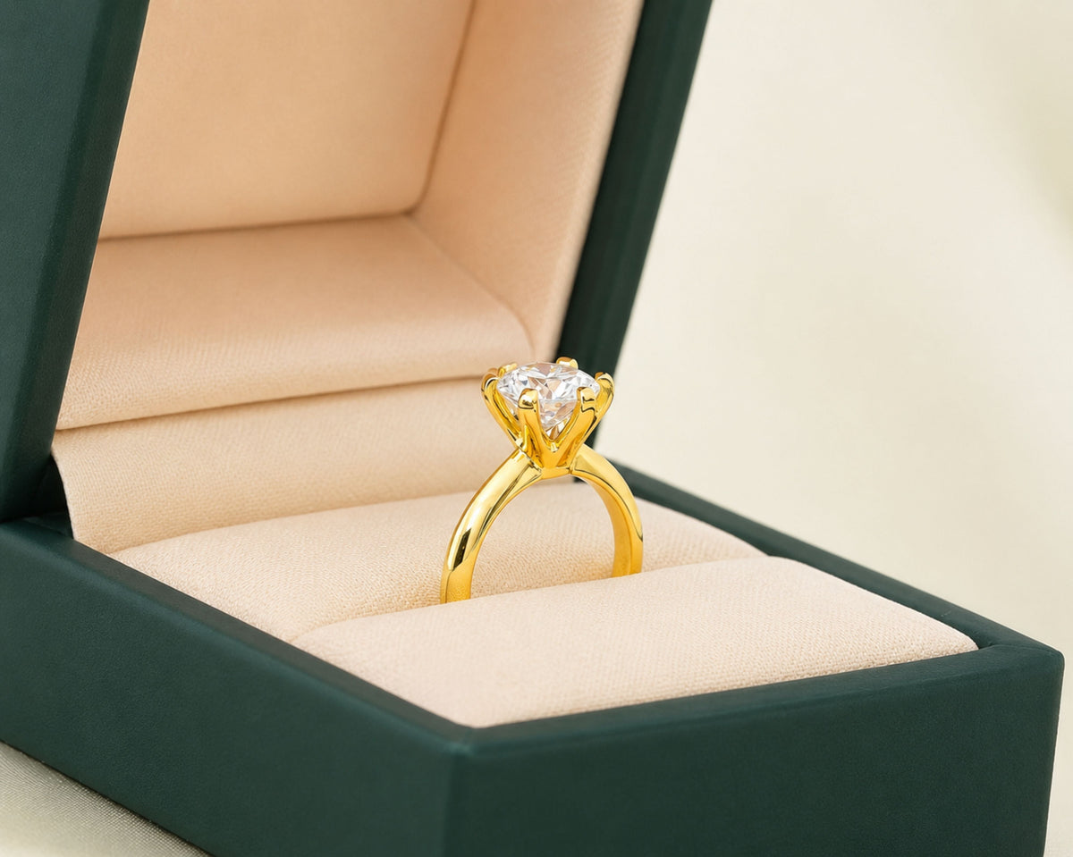 Gold solitaire engagement ring with a round diamond in an open jewelry box