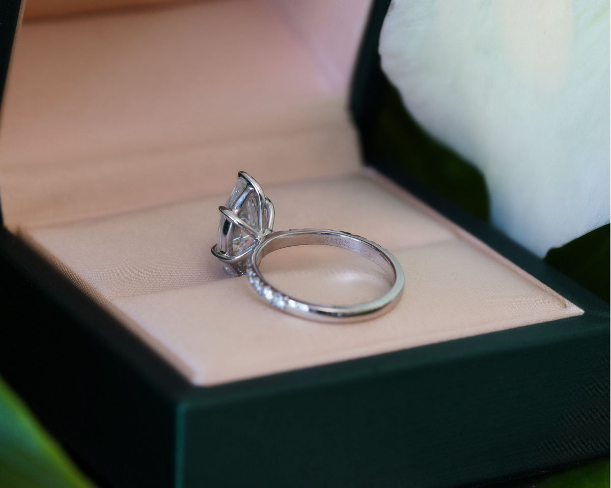 Marquise solitaire engagement ring in a luxury ring box featuring a cathedral setting with a hidden halo and pavé diamond band.
