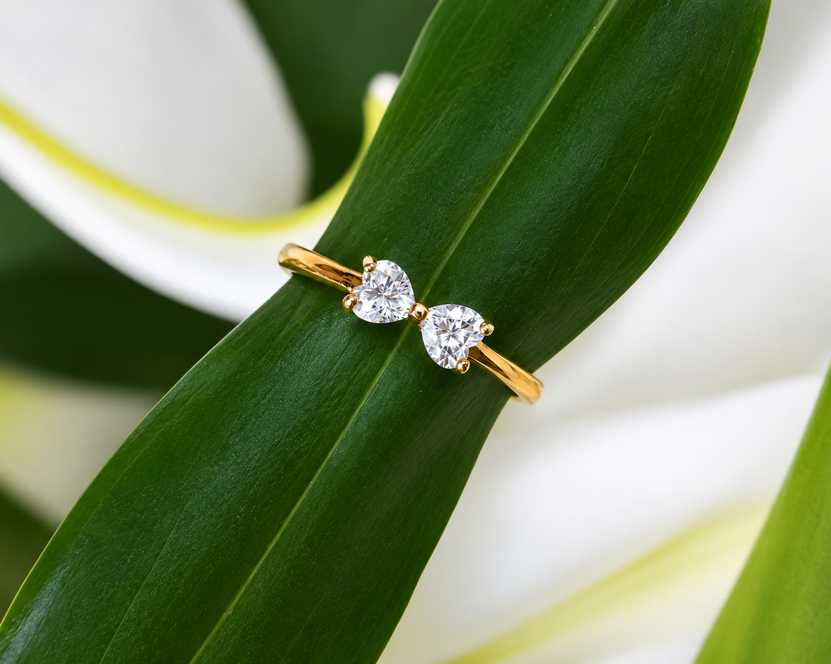 Two-stone diamond ring in yellow gold displayed on green leaf