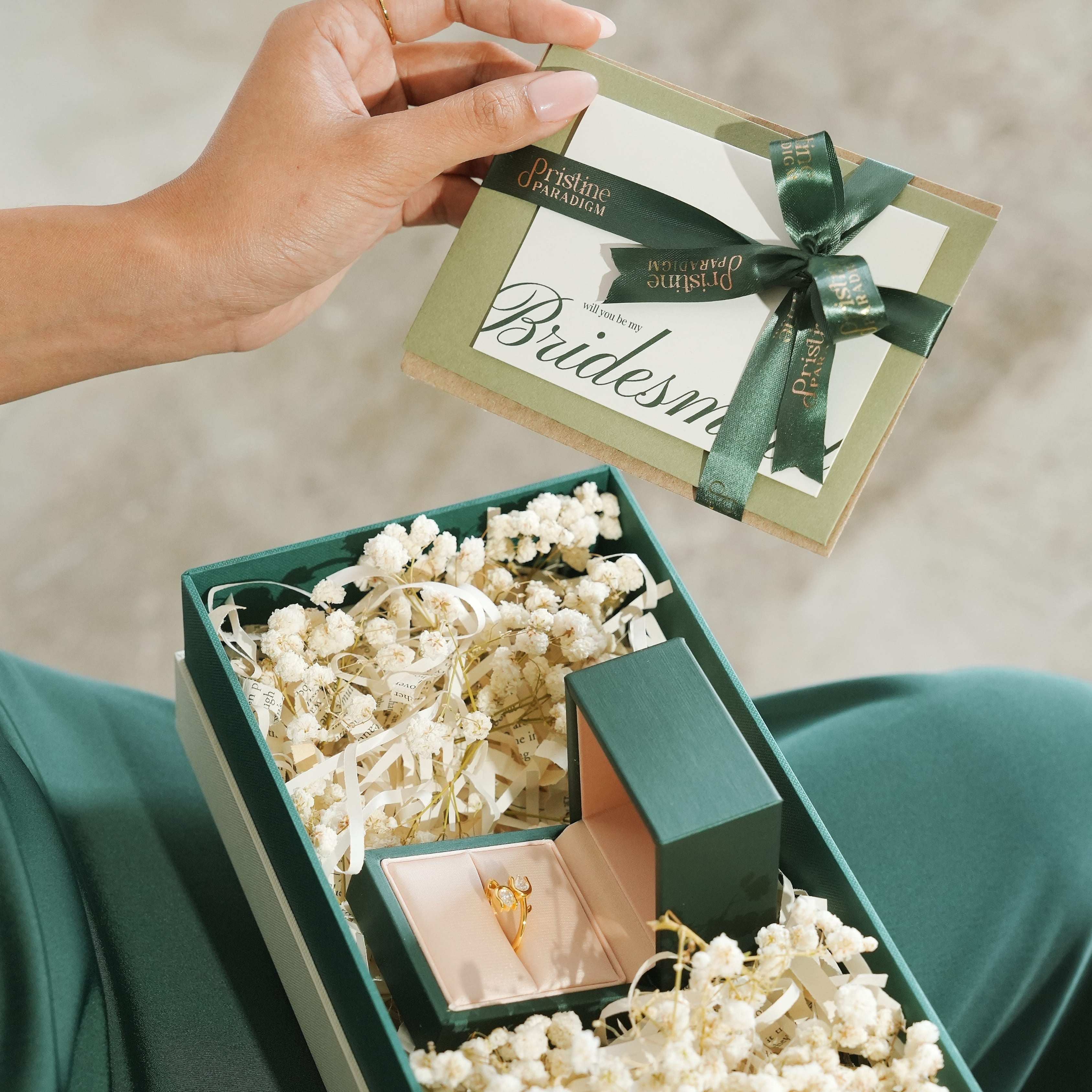 Green jewelry box with a lab-grown diamond ring and gift card on a neutral background