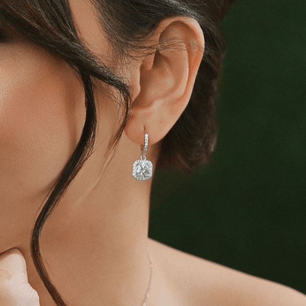 Close-up of a diamond dangling earring with a lab-grown stone, worn on a model's ear